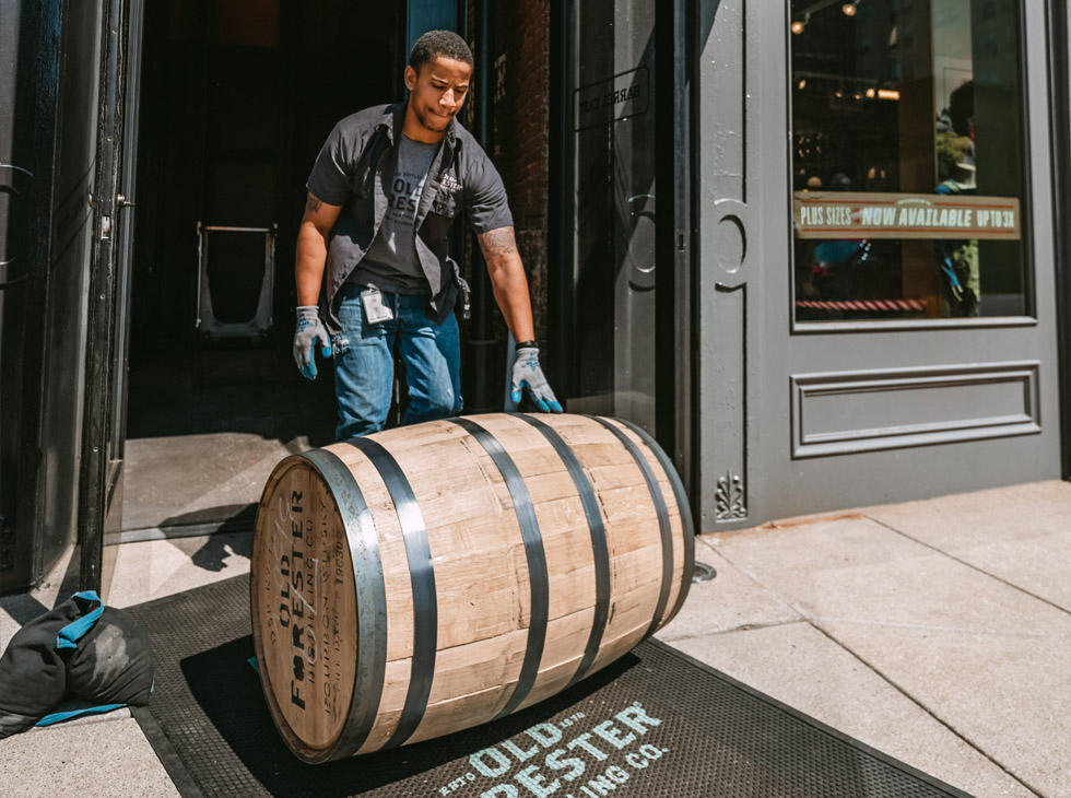 Man rolling Old Forester barrel out of Distillery